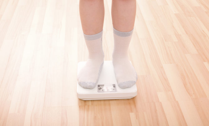Boy measures weight on floor scales